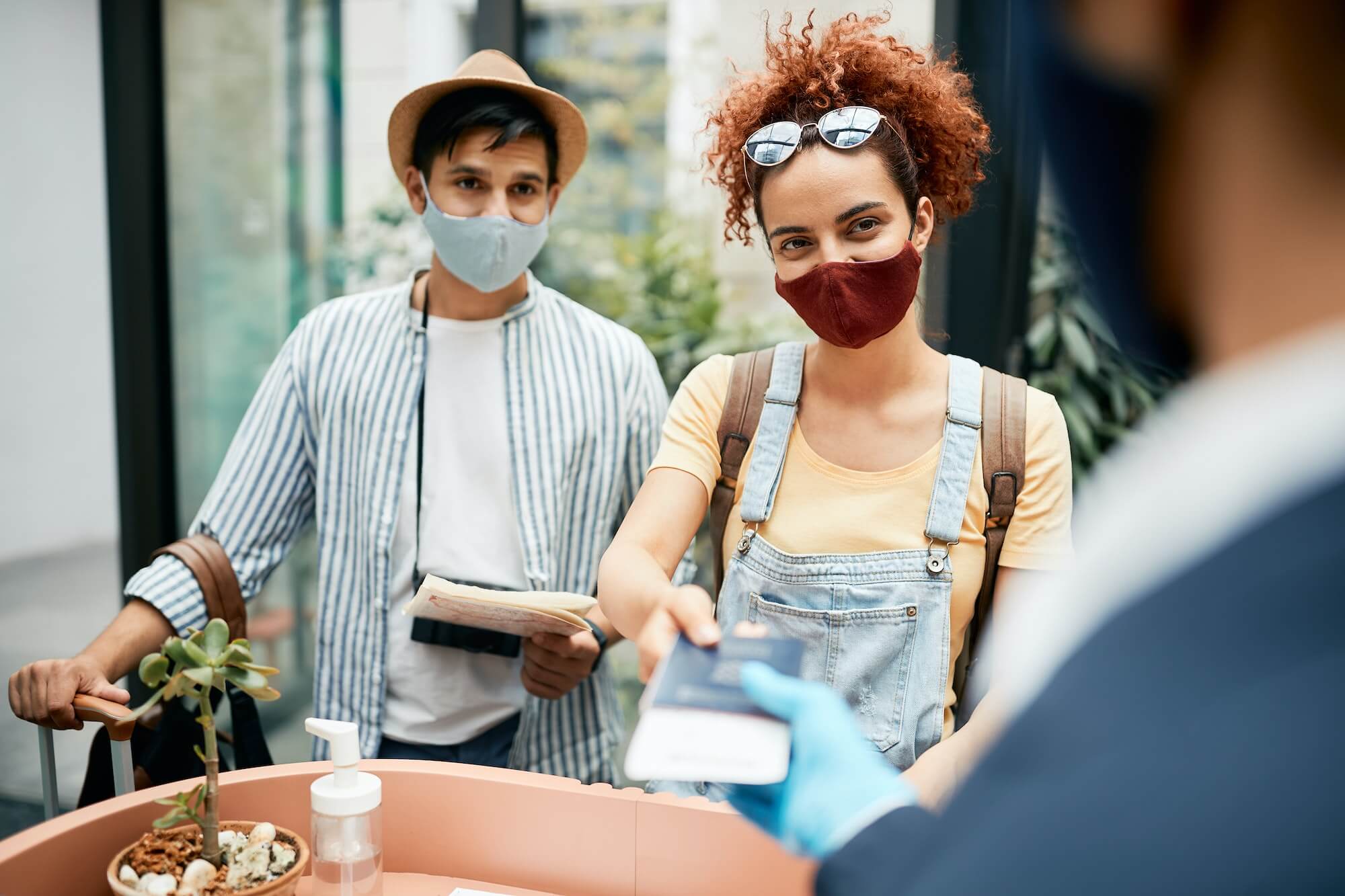 young-traveling-couple-wearing-protective-face-mask-during-check-in-at-hotel-reception-1-1.jpg